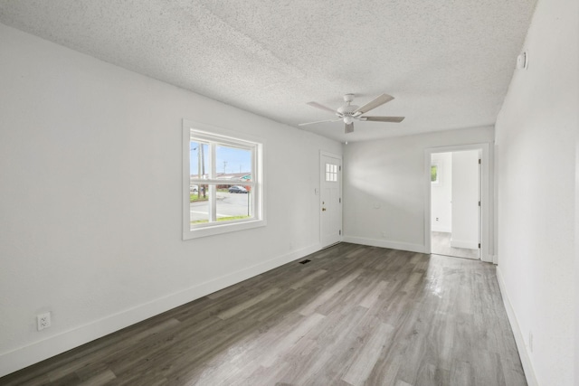 empty room with a ceiling fan, baseboards, wood finished floors, and a textured ceiling