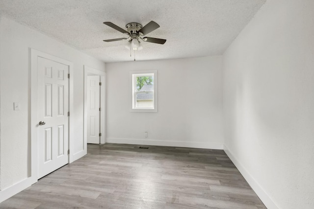 unfurnished bedroom with baseboards, wood finished floors, ceiling fan, and a textured ceiling