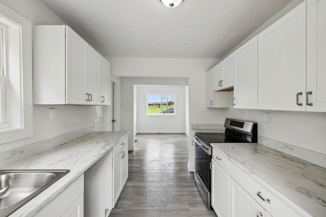 kitchen featuring electric stove, light wood-style flooring, white cabinets, a sink, and a textured ceiling