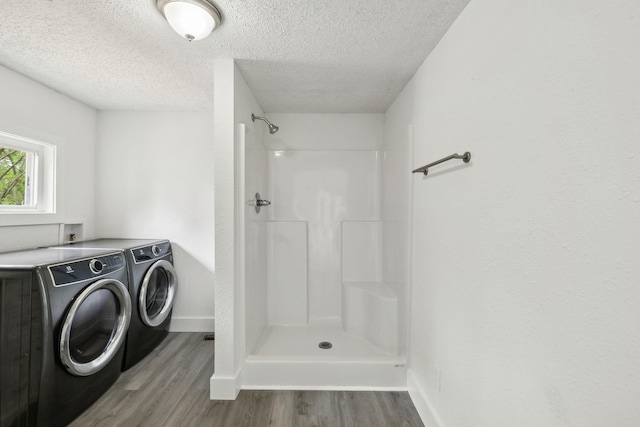 laundry area with wood finished floors, laundry area, washing machine and clothes dryer, baseboards, and a textured ceiling