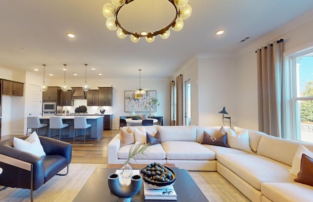 living room with visible vents, crown molding, light wood finished floors, and recessed lighting