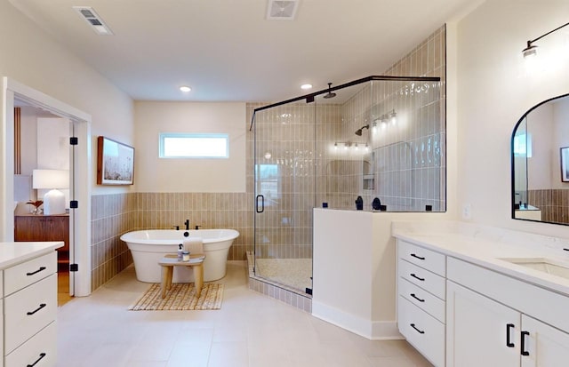 full bathroom featuring visible vents, a freestanding bath, a shower stall, and vanity