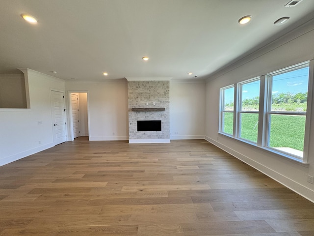 unfurnished living room featuring recessed lighting, a fireplace, baseboards, ornamental molding, and wood finished floors