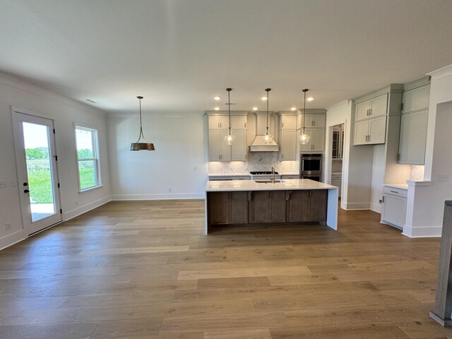 kitchen featuring decorative backsplash, light wood-style floors, light countertops, and baseboards