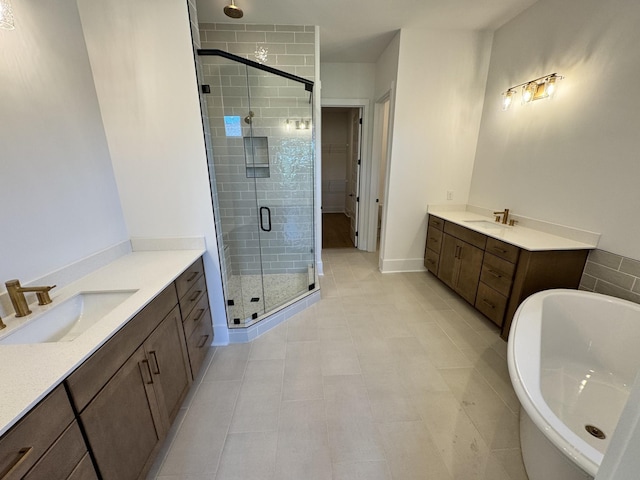 full bathroom featuring a stall shower, two vanities, a sink, and a freestanding bath