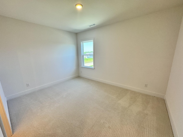 spare room with baseboards, visible vents, and light colored carpet