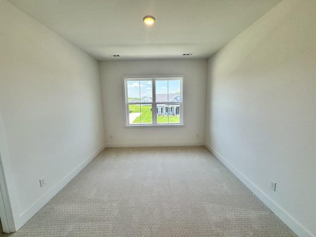 spare room with visible vents, light colored carpet, and baseboards