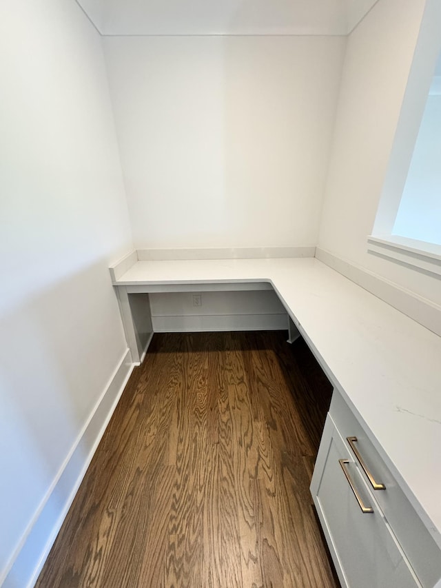 unfurnished office with dark wood-style floors and baseboards