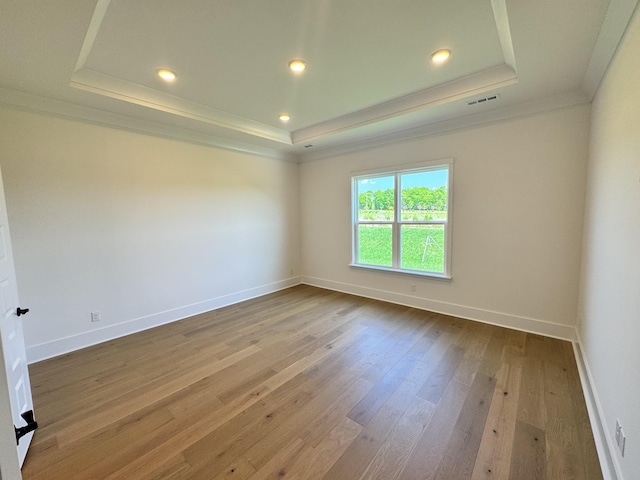 spare room featuring recessed lighting, wood-type flooring, a raised ceiling, visible vents, and ornamental molding