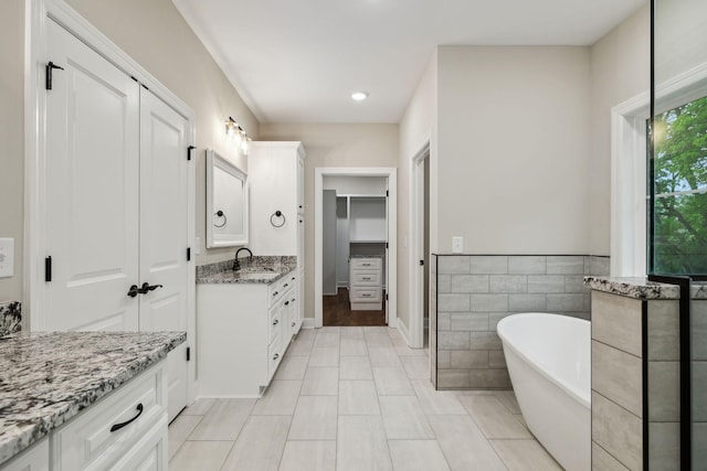 8020 Traditions Ln, Columbia, TN 38401 - bathroom with tile walls, vanity, a freestanding tub, a walk in closet, and tile patterned flooring