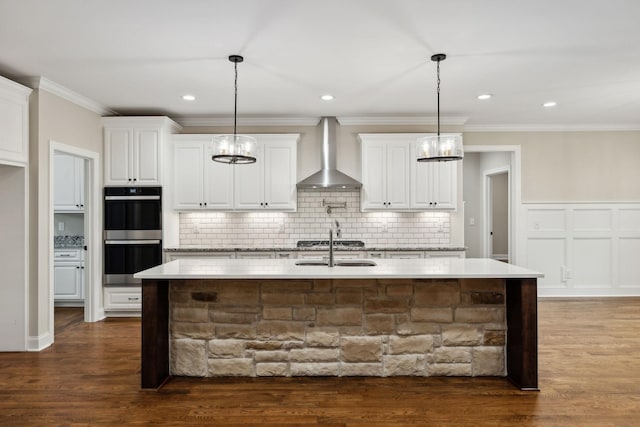 8020 Traditions Ln, Columbia, TN 38401 - kitchen with wall chimney range hood, white cabinetry, stainless steel double oven, an island with sink, and backsplash