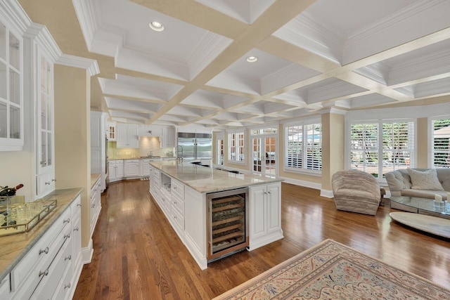 kitchen featuring dark wood finished floors, beverage cooler, glass insert cabinets, beam ceiling, and open floor plan