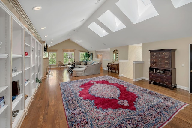 living area with wood finished floors, baseboards, and vaulted ceiling with skylight