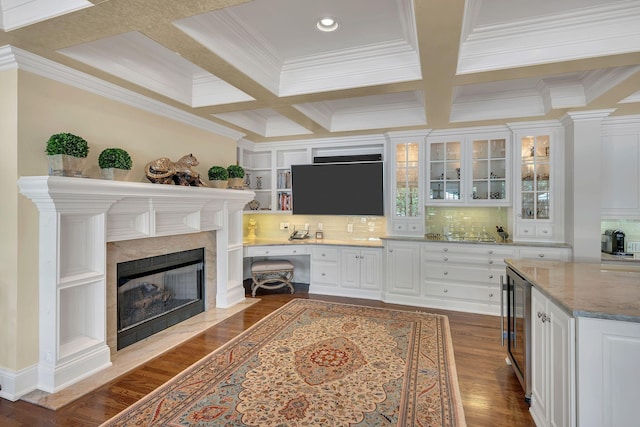 interior space with tasteful backsplash, coffered ceiling, ornamental molding, white cabinets, and beverage cooler