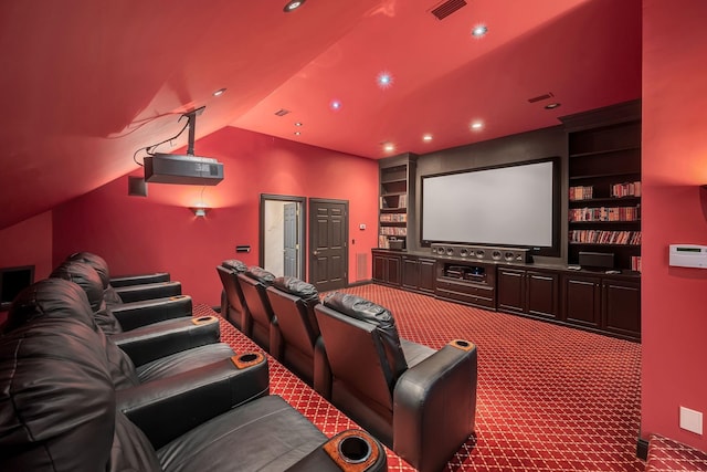 carpeted cinema featuring visible vents, built in shelves, and vaulted ceiling