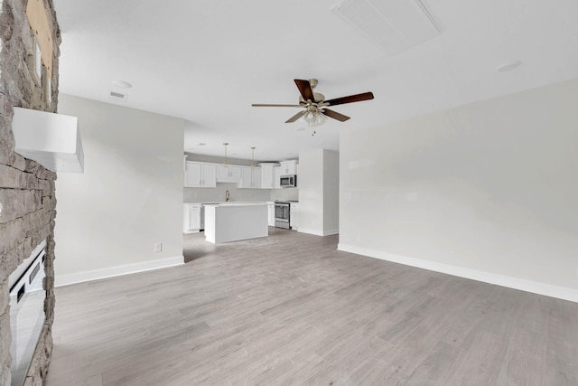 500 Herman Dr, Clarksville, TN 37042 - unfurnished living room featuring a large fireplace, baseboards, ceiling fan, light wood finished floors, and a sink