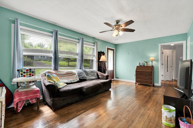 living room with a textured ceiling, ceiling fan, baseboards, and wood-type flooring