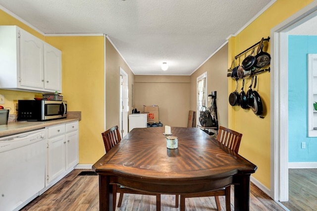 dining room with baseboards, crown molding, a textured ceiling, and light wood-style flooring