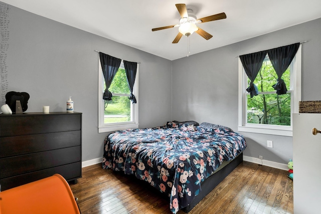 bedroom with baseboards, hardwood / wood-style flooring, and multiple windows