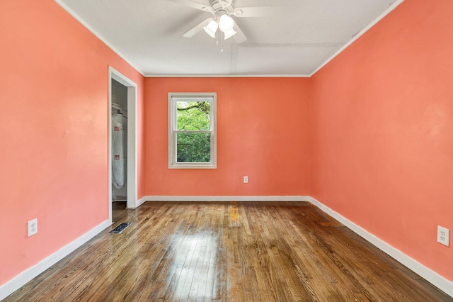 empty room with ornamental molding, wood-type flooring, baseboards, visible vents, and a ceiling fan