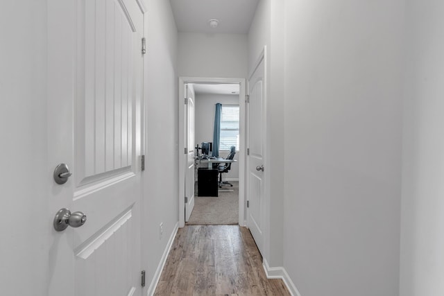 hallway featuring baseboards and wood finished floors