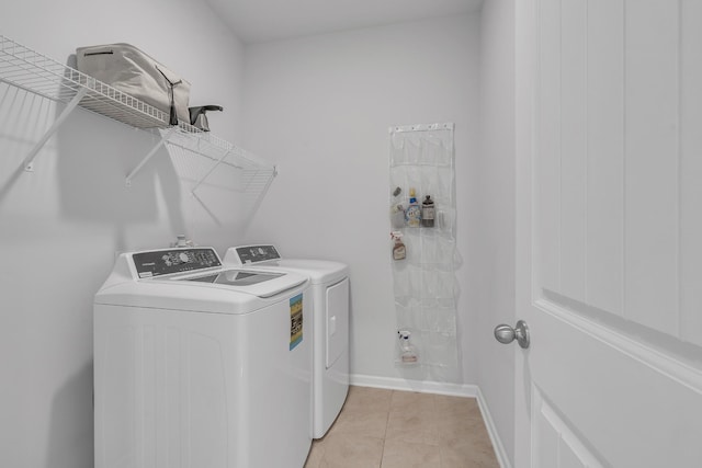 laundry area with light tile patterned floors, baseboards, laundry area, and washing machine and clothes dryer