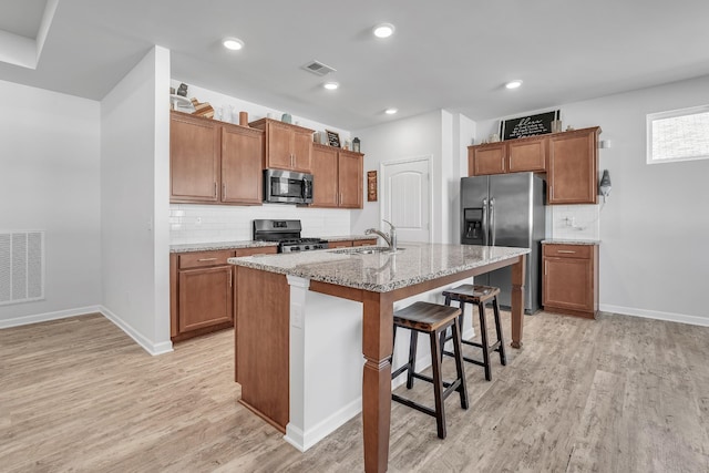 kitchen featuring appliances with stainless steel finishes, light wood finished floors, a sink, and visible vents