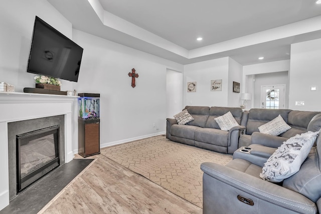 living area with recessed lighting, baseboards, a glass covered fireplace, and wood finished floors