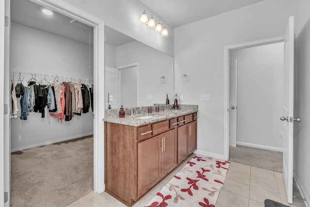 bathroom featuring vanity, baseboards, tile patterned floors, and a spacious closet