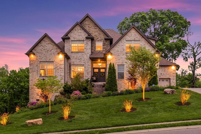 view of front of property featuring a yard, brick siding, and a garage
