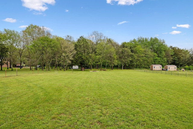 view of yard featuring an outbuilding, a storage shed, and fence