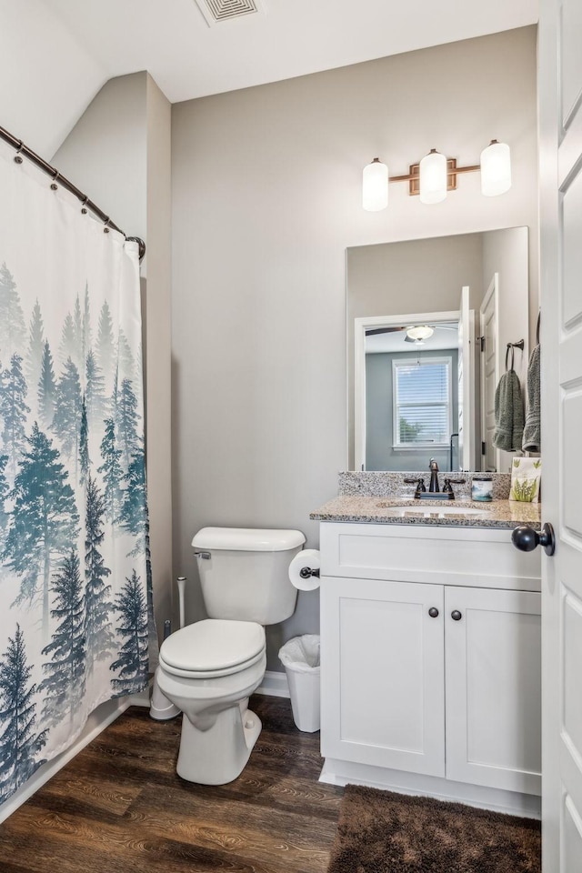 bathroom featuring curtained shower, visible vents, toilet, wood finished floors, and vanity