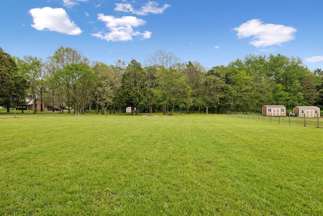 view of yard featuring fence, a storage unit, and an outbuilding