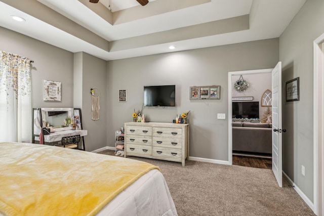 carpeted bedroom with recessed lighting, a raised ceiling, and baseboards
