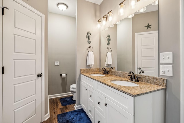 full bathroom featuring double vanity, wood finished floors, toilet, and a sink
