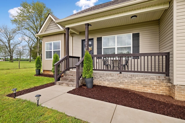 view of exterior entry featuring a yard and covered porch