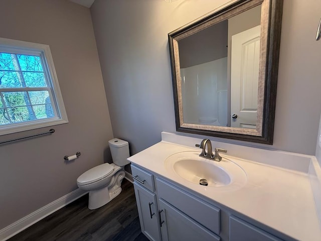 bathroom with wood finished floors, toilet, vanity, and baseboards