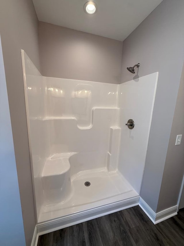 bathroom featuring a shower, wood finished floors, and baseboards
