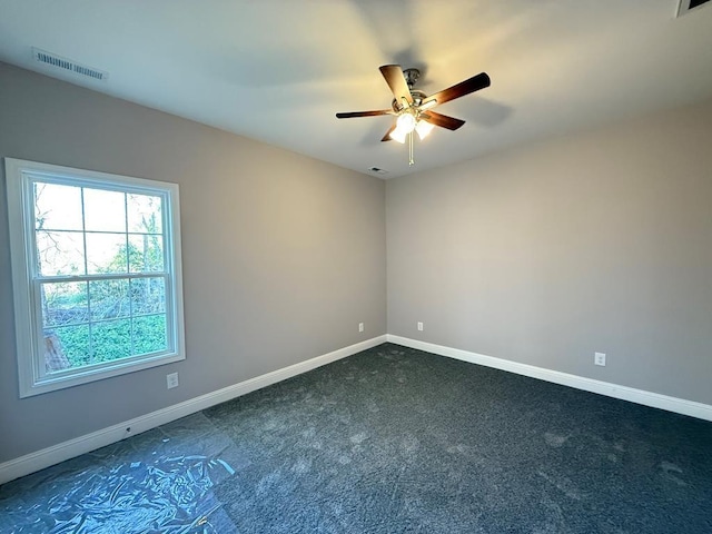 unfurnished room featuring baseboards, visible vents, dark colored carpet, and a ceiling fan