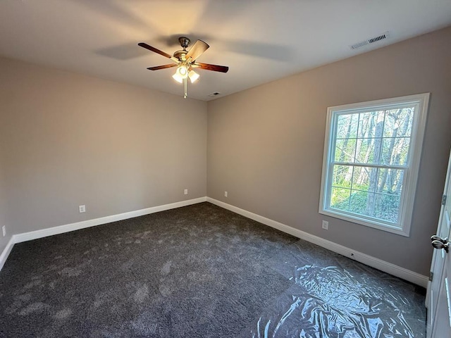spare room with baseboards, visible vents, dark colored carpet, and ceiling fan