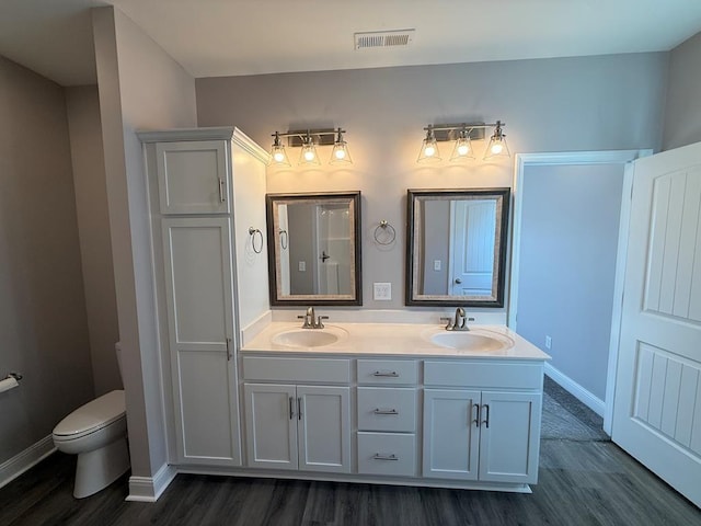 full bath featuring double vanity, a sink, wood finished floors, and visible vents