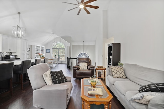 living room featuring lofted ceiling, dark wood-style floors, and ceiling fan with notable chandelier