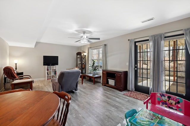 living area with visible vents, a ceiling fan, light wood-style flooring, and baseboards
