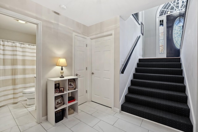 stairway with marble finish floor and baseboards