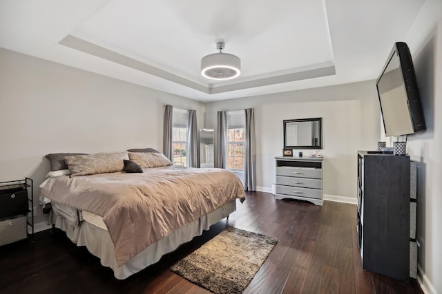 bedroom with ornamental molding, baseboards, a raised ceiling, and dark wood-type flooring