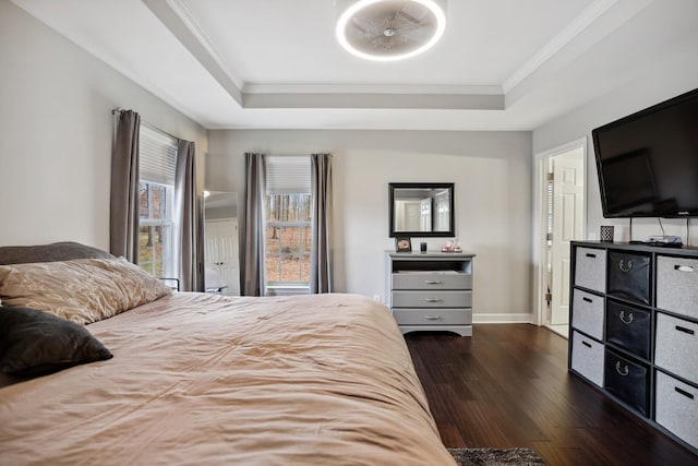 bedroom featuring dark wood finished floors, baseboards, a raised ceiling, and crown molding