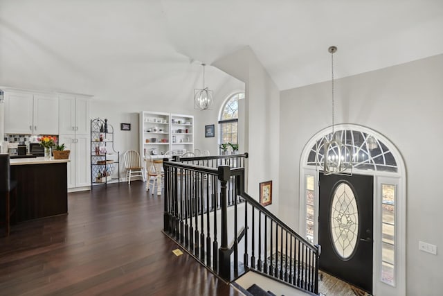 foyer featuring a notable chandelier, dark wood-type flooring, and vaulted ceiling