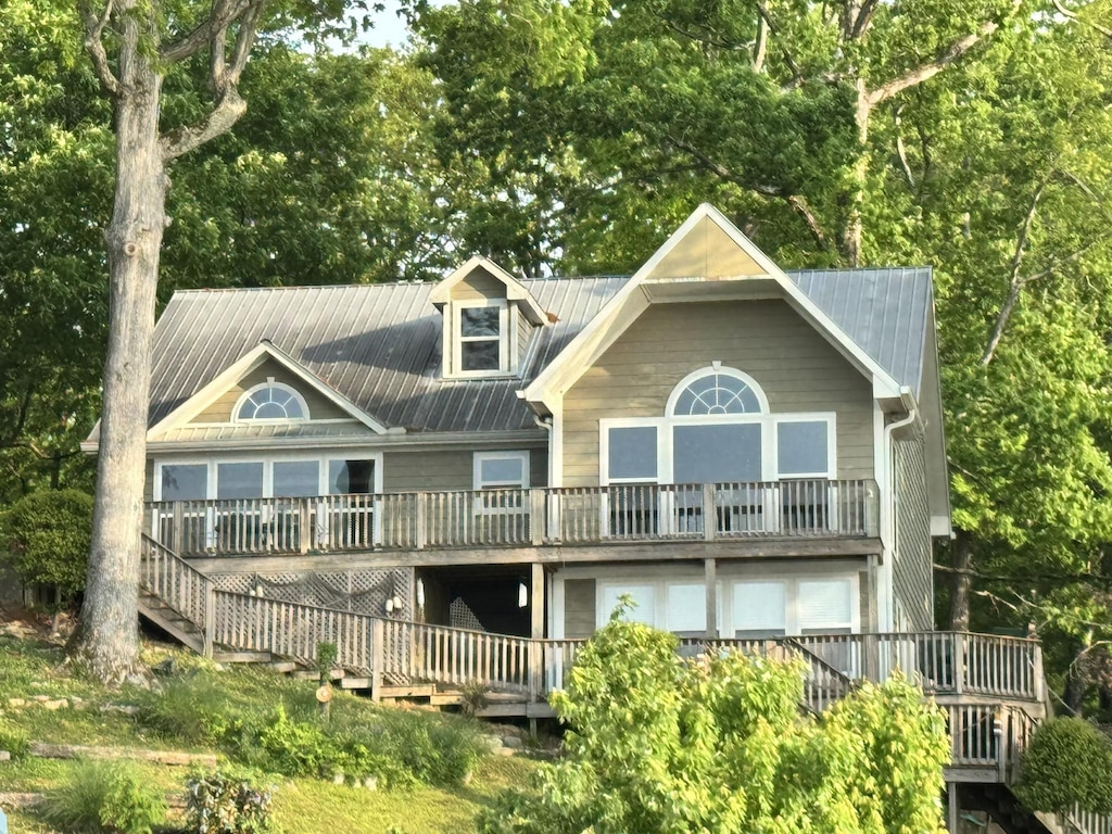 back of property featuring stairway, metal roof, and a wooden deck