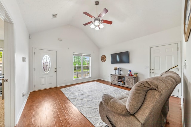 living room featuring wood finished floors, vaulted ceiling, ceiling fan, baseboards, and visible vents