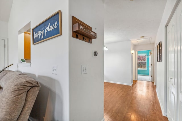 hall with attic access, wood finished floors, and baseboards
